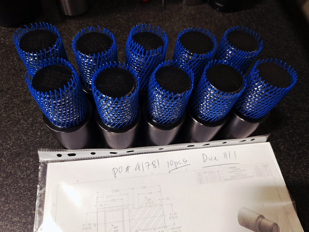 Finished parts in protective netting with the job paperwork, ready to ship